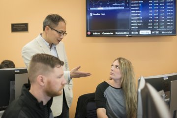 Business Prof Zhaodan Huang talks with student Stock info behind