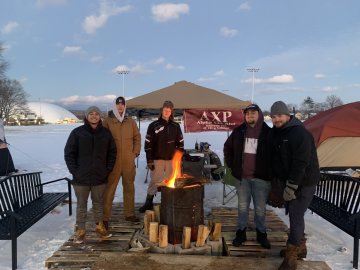 Members of AXP stand out int he cold by a fire. 