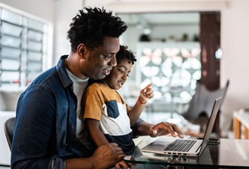 Father and son sitting together at computer