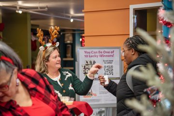Students enter the dining hall, greeted by faculty at the 2025 Holiday Dinner.