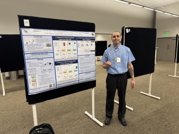 Fausto Martinez stands by research poster at 33rd Annual Animal Behavior Conference.