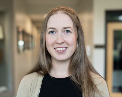 Alicia Reed, with long hair, a black top and tan sweater.