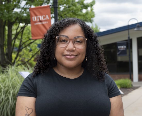 Nevaeh Scott-Dominguez stands in front of a Utica University banner on campus.