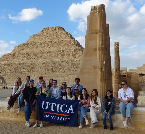 Students hold up a Utica University banner at Saqqara during a January 2023 trip to Egypt.